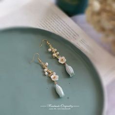 a pair of earrings sitting on top of a plate next to a cup and book