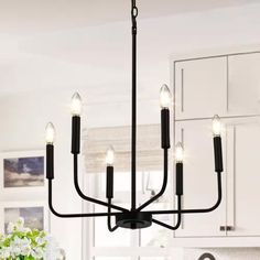 a black chandelier with five lights hanging from it's center piece in a kitchen