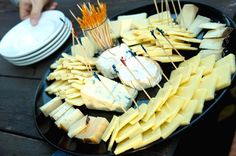 cheese and crackers are arranged on a black platter with toothpicks in them