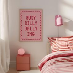 a bedroom with pink and white decor, striped bedding and a framed poster on the wall