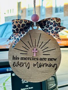 a wooden sign hanging from the side of a car with a leopard print bow on it