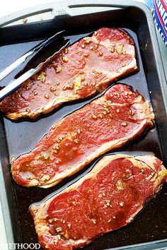 two raw meats in a pan with sauce and seasoning on the side, ready to be cooked