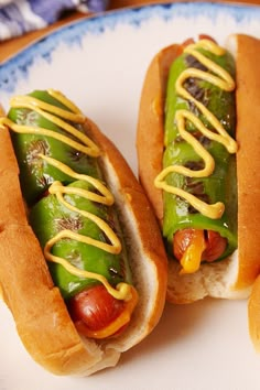 two hot dogs on buns with mustard and ketchup sitting on a plate