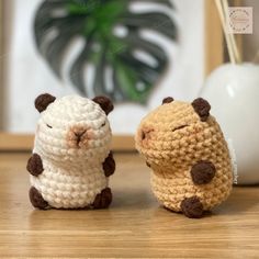 two small crocheted animals sitting next to each other on top of a wooden table