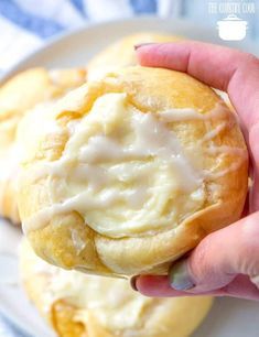 a hand holding a pastry with cream cheese on it