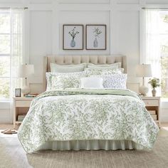 a bed with green and white bedspread in a bedroom next to two windows