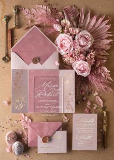 pink and gold wedding stationery with flowers on the bottom right hand corner is an envelope