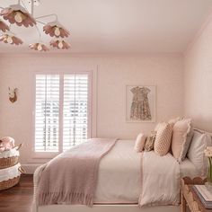 a bedroom decorated in pink and white with flowers on the ceiling, bedding, and window