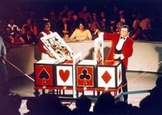 a man in a red suit standing next to a table with playing cards on it