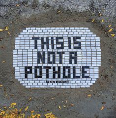 this is not a pothole sign on the side of a brick wall that reads, this is not a pothole