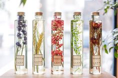 four glass bottles filled with different types of flowers