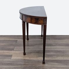 an oval shaped wooden table sitting on top of a hard wood floor