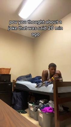 a man laying on top of a bed next to a wooden desk and chair in a room