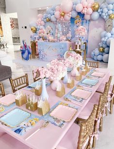 a table set up for a princess party with pink and blue decorations, gold plates and napkins