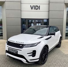 a white range rover is parked in front of a dealership with black rims