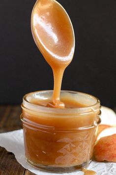 a spoon full of caramel sauce on top of an apple