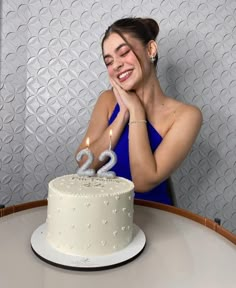 a woman sitting in front of a white cake