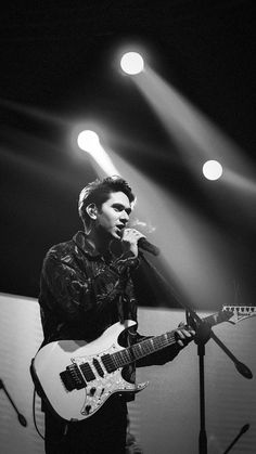 a man singing into a microphone while holding a guitar