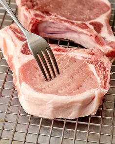 two pieces of raw meat on a rack with a fork