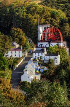 an aerial view of a town surrounded by trees and hills with a ferris wheel in the background