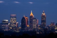 the city skyline is lit up at night, with skyscrapers in the foreground