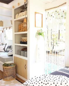 a room with a bed, shelves and baskets on the floor next to a door