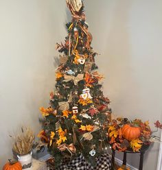 a decorated christmas tree in the corner of a room with pumpkins and other decorations