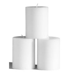 three white candles sitting on top of each other in front of a white background with the candle lit