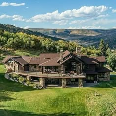 an aerial view of a large home in the middle of a green field with mountains in the background