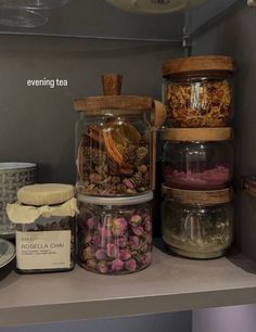 several jars filled with different types of teas on a shelf in a kitchen area