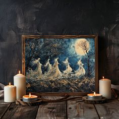 three lit candles sitting on top of a wooden table next to a painting with women in white dresses