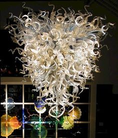 a chandelier hanging from the ceiling in a room with glass windows and flowers