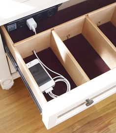 an open drawer with two cell phones in it and cords plugged into the drawers