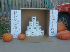 a cardboard box filled with toilet paper rolls and pumpkins on the ground next to it