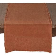 a brown table runner on top of a wooden table with an orange cloth over it