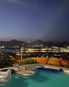 an outdoor swimming pool at night overlooking the city lights