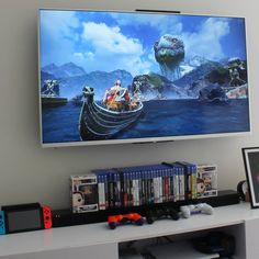 a flat screen tv mounted on the wall above a white entertainment center with video games