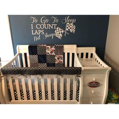 a white crib with black and white checkered bedding in front of a blue wall