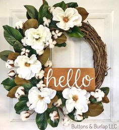 a wreath with the word hello painted on it and white flowers in front of it