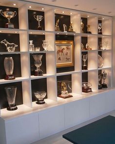 a room filled with lots of glass vases and trophies on top of bookshelves