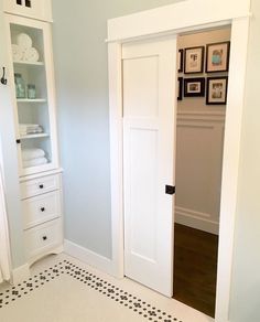 an open door leading to a bathroom with black and white floor tiles on the floor