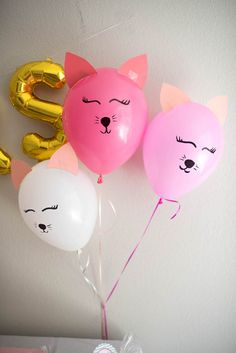 three balloons in the shape of cats and numbers