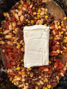 beans, tomatoes, corn and cheese in a skillet with a white square on top