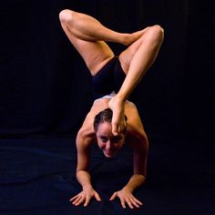 a woman is doing a handstand on the floor in front of a black background