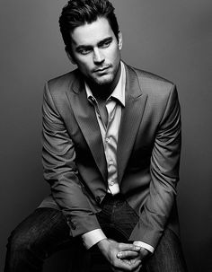 a man in a suit and tie sitting on a stool