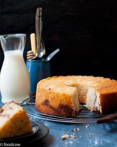 a cake sitting on top of a cooling rack next to a glass of milk and a bottle