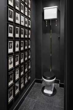 a black and white bathroom with pictures on the wall, toilet seat cover and roll of toilet paper