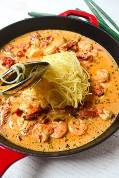 a pan filled with pasta and shrimp on top of a table