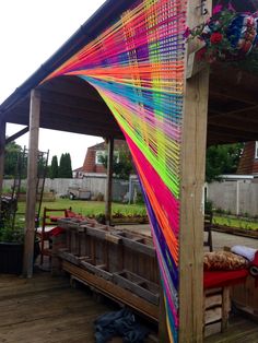 a rainbow colored structure on a deck in the middle of a yard with benches and tables