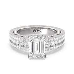 a white gold ring with an emerald cut diamond and pave set diamonds on the sides